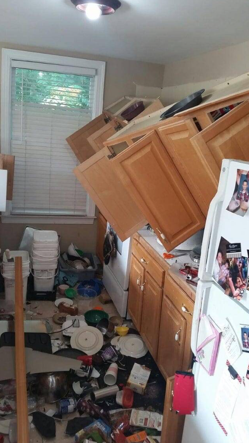 V kuchyni padli skrinky, riad a jedlo sú rozhádzané po zemi, chaos v miestnosti.