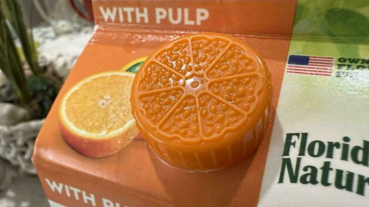 Vrchnák džúsu v tvare pomaranča na kartóne s označením with pulp a logom americkej vlajky.