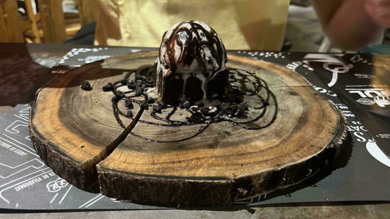 Dezert s čokoládovou polevou a zmrzlinou na drevenom tanieri.