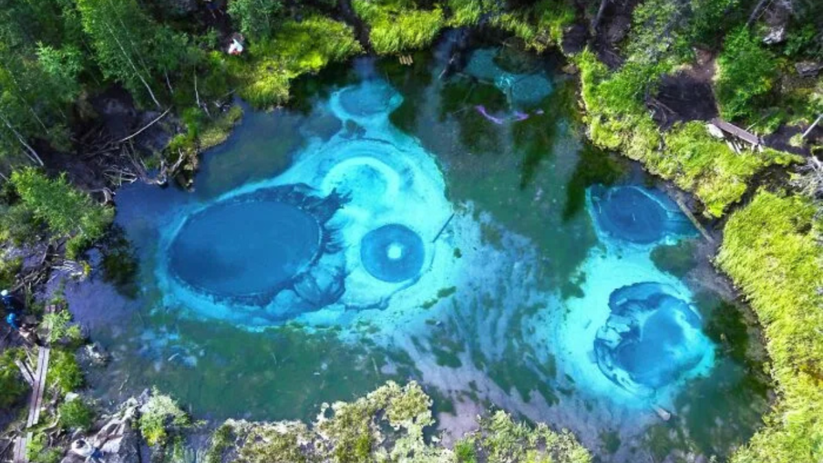 Tyrkysové termálne jazierko obklopené lesom, pohľad zhora, prírodný jav.