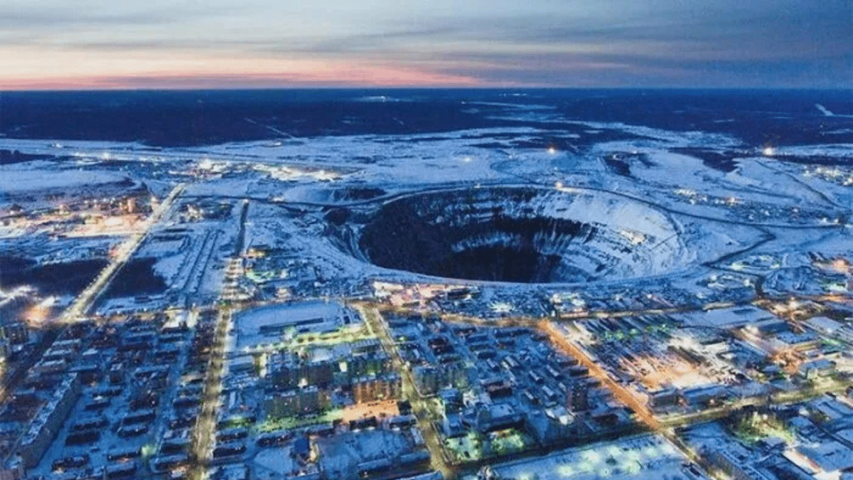 Letecký pohľad na zasneženú krajinu s obrovským banským kráterom v strede.
