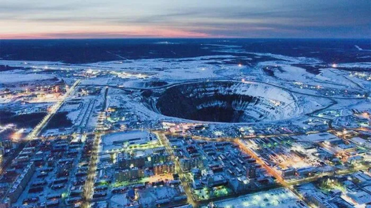 Letecký pohľad na zasneženú krajinu s obrovským banským kráterom v strede.