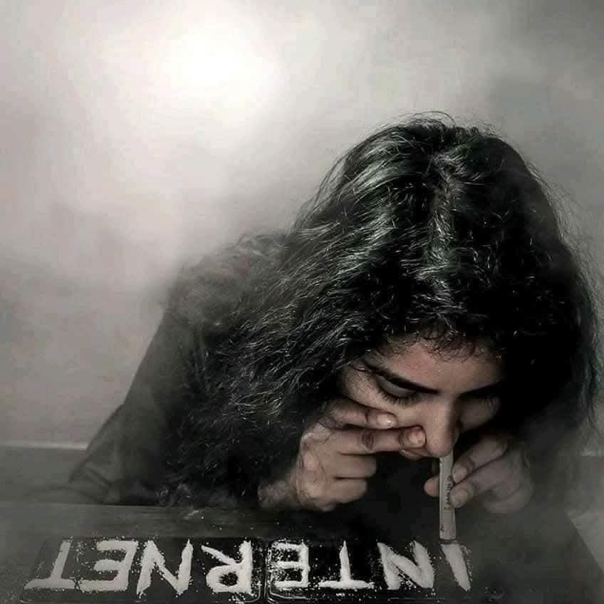 Osoba symbolizujúca závislosť na internete pomocou nápisu vytvoreného z prášku na stole.