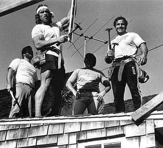 Skupina mužov pracuje na streche s nástrojmi v rukách, čiernobiela fotografia z doby XX. storočia.