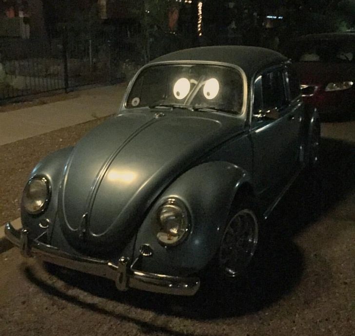 Klasický Volkswagen Beetle s nalepenými očami na čelnom skle pôsobí večer ako animovaný.
