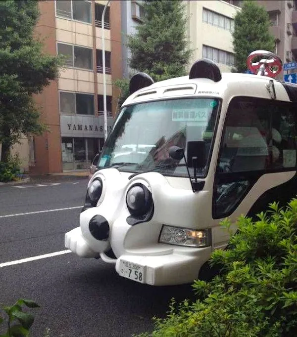 Autobus v tvare pandy stojí na ulici medzi budovami.