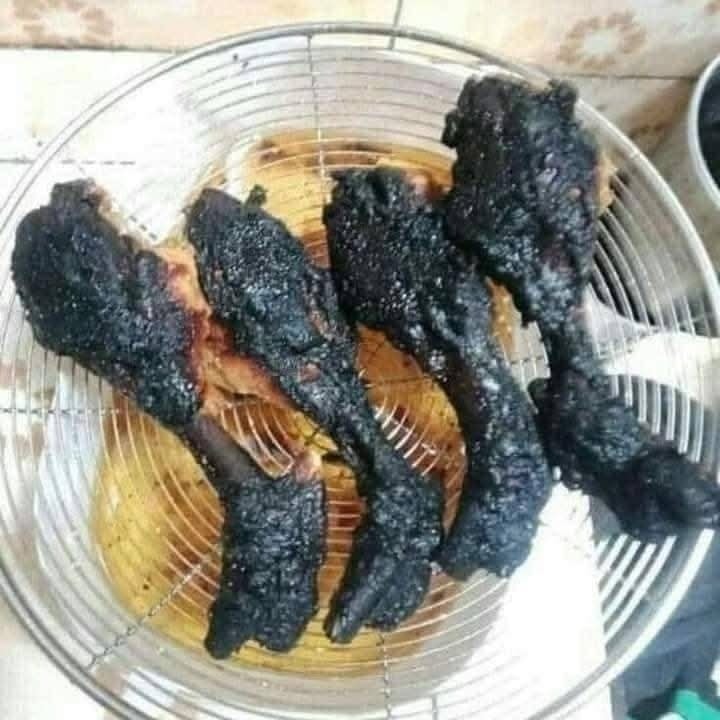 Spálené kuracie stehná na kovovej mriežke v kuchyni.