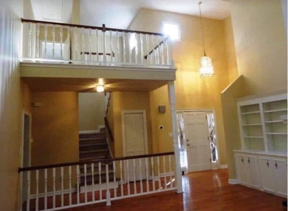 Interiér svetlej haly s dreveným schodiskom, vstupnými dverami a zabudovanými policami.