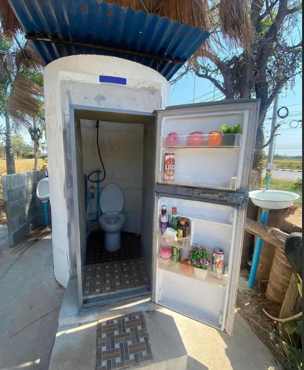 Exteriérová toaleta s dverami z chladničky, zaujímavá kombinácia dizajnu na skromnom mieste.