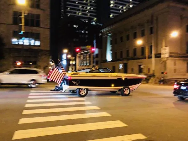 Loď na cestnom priechode s americkou vlajkou v nočnom meste.