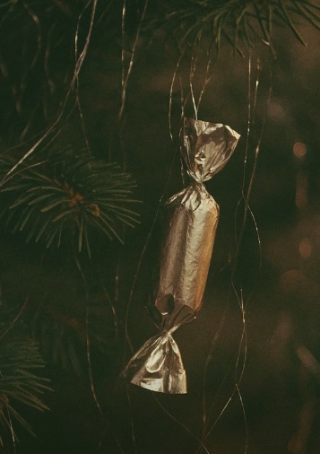 Vianočná salónka vo zlatej fólii zavesená na ihličnatom strome, symbol tradičných sviatkov.