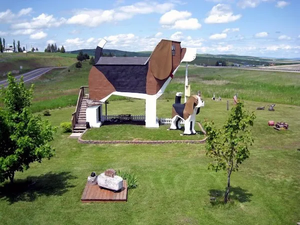 Unikátna stavba v tvare psa na zelenej lúke, ideálna pre cestovateľov a milovníkov architektúry.