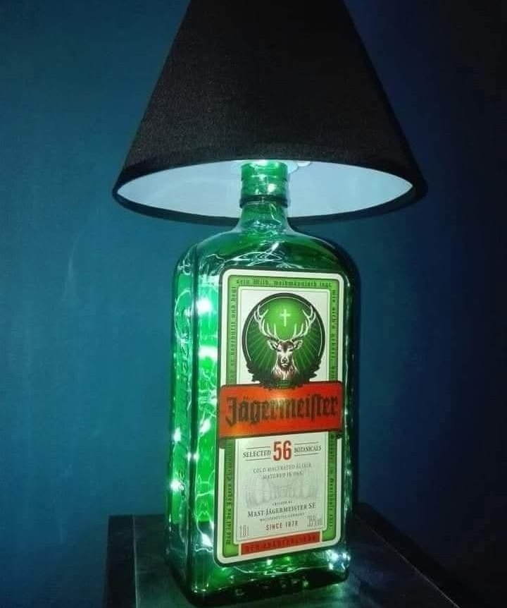 Lampa z fľaše likéru s čiernym tienidlom na modrom pozadí, kreatívny nápad na recykláciu fľaše.