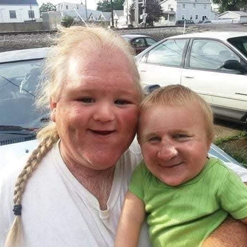 Ľudia s vtipne upravenými tvárami stoja pri aute, oblečení v bielom a zelenom tričku, prirodzené prostredie.