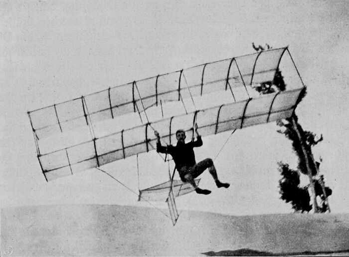 Muž v klzáku z 19. storočia letí vo vzduchu, ilustruje počiatky letectva. Vintage fotografia experimentálneho lietania.