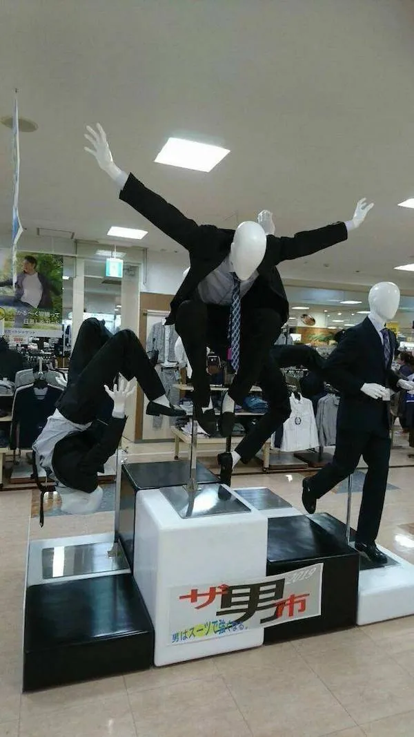 Figuríny v oblekoch v dynamických pózach vytvárajú kreatívny výstavný prvok v obchode s pánskou módou.