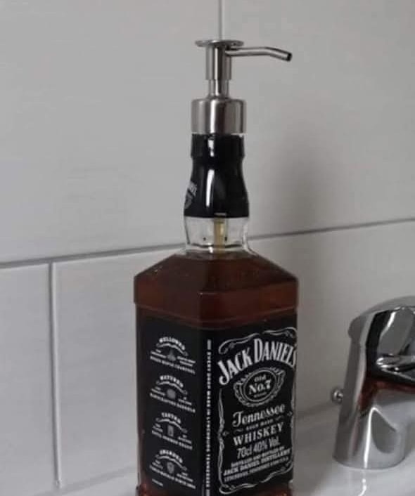 Fľaša s označením whisky upravená na dávkovač mydla na umývadle.