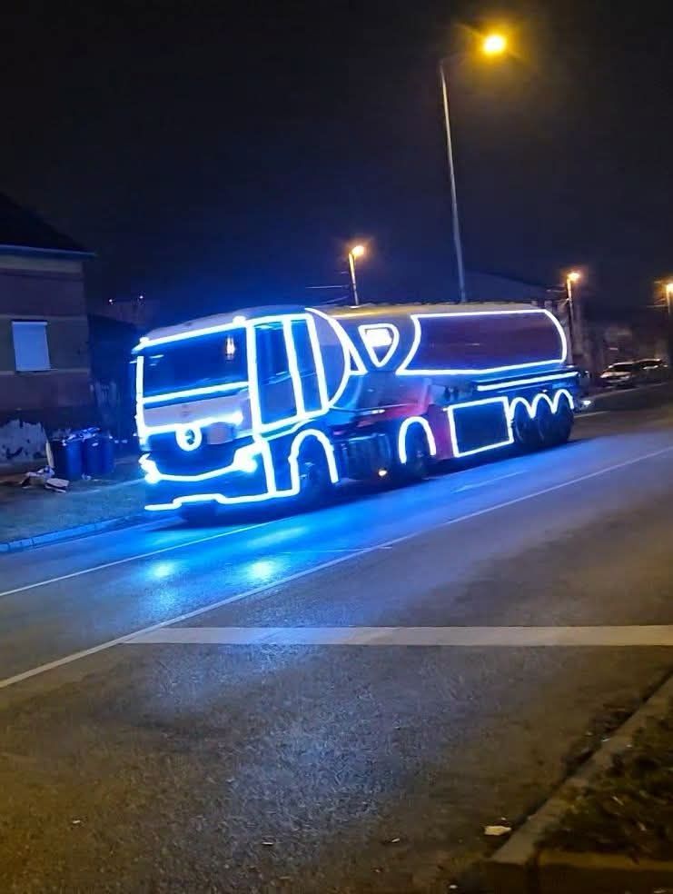 Osvetlený kamión v noci, vyzdobený jasnými modrými svetlami na ceste.