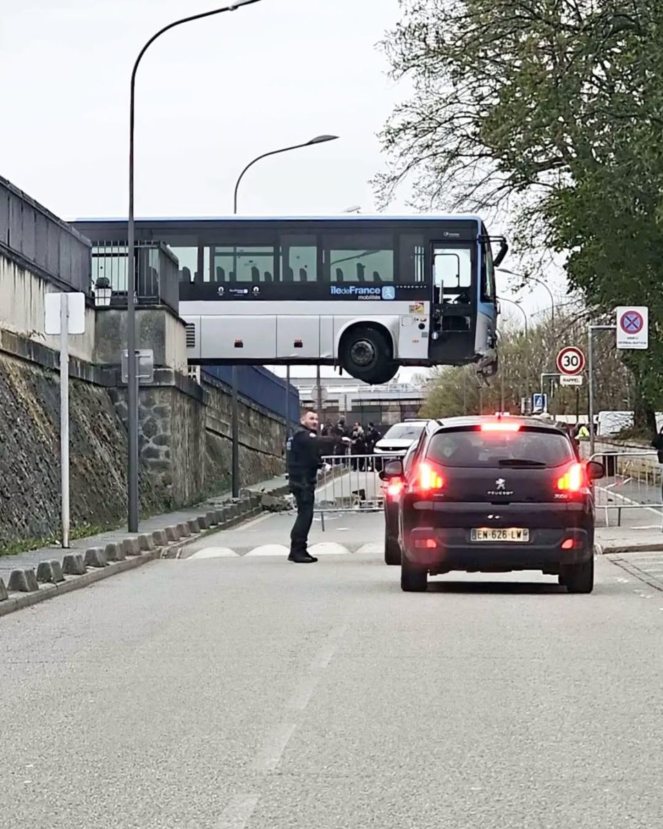 Autobus zaseknutý na moste, zatiaľ čo polícia riadi premávku na ceste s autami čakajúcimi v rade.