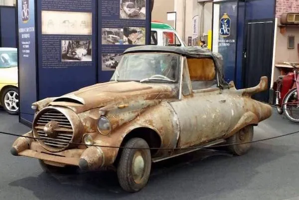 Staré, zhrdzavené auto vystavené v múzeu, ukazuje svoj unikátny dizajn a patinu minulých rokov.