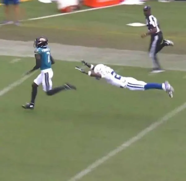 Futbalista uniká obrancovi na ihrisku počas zápasu NFL. Trávnik a tribúny sú v pozadí.