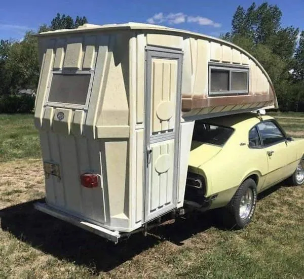 Auto s originálnym obytným prívesom na poli, kreatívny cestovateľský dizajn.