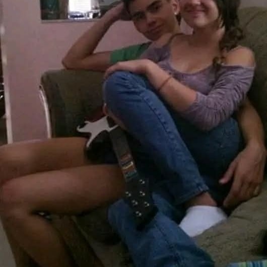 Dvom mladým ľuďom sedieť na pohovke v obývačke s hernou gitarou v priaznivej atmosfére.