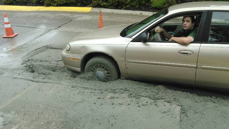 Auto zapadnuté v čerstvo vylievanom betóne na ceste, vodič hľadá spôsob, ako sa dostať von.