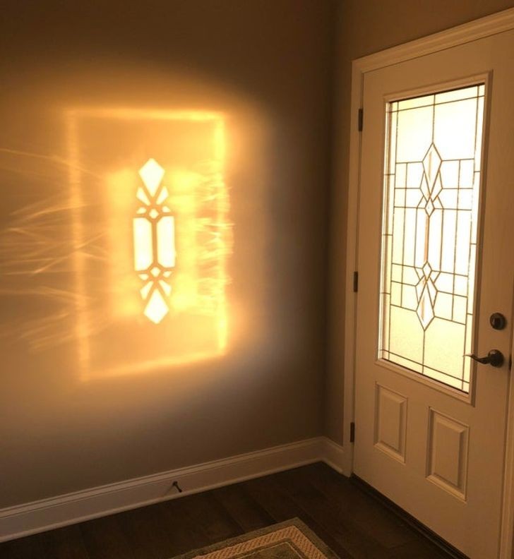 Slnečné svetlo prechádza cez sklenené dvere a vytvára svetelný vzor na stene v predsieni.