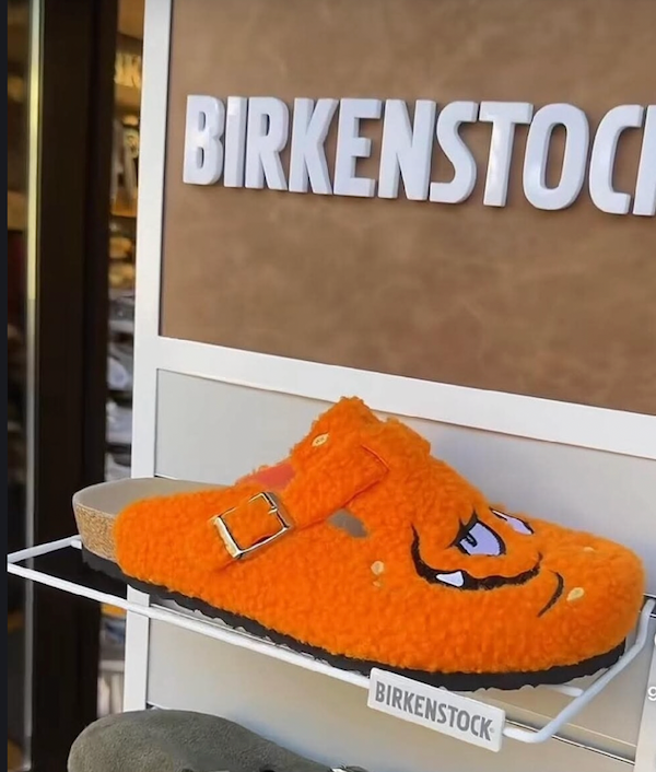 Oranžový papuče Birkenstock s veselým kresleným motívom vystavený v obchode.