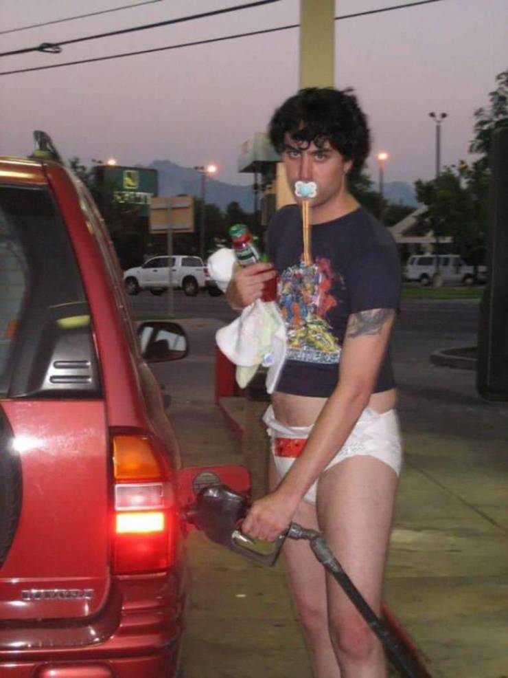 Muž oblečený neobvykle stojí pri čerpacej stanici a tankuje auto.