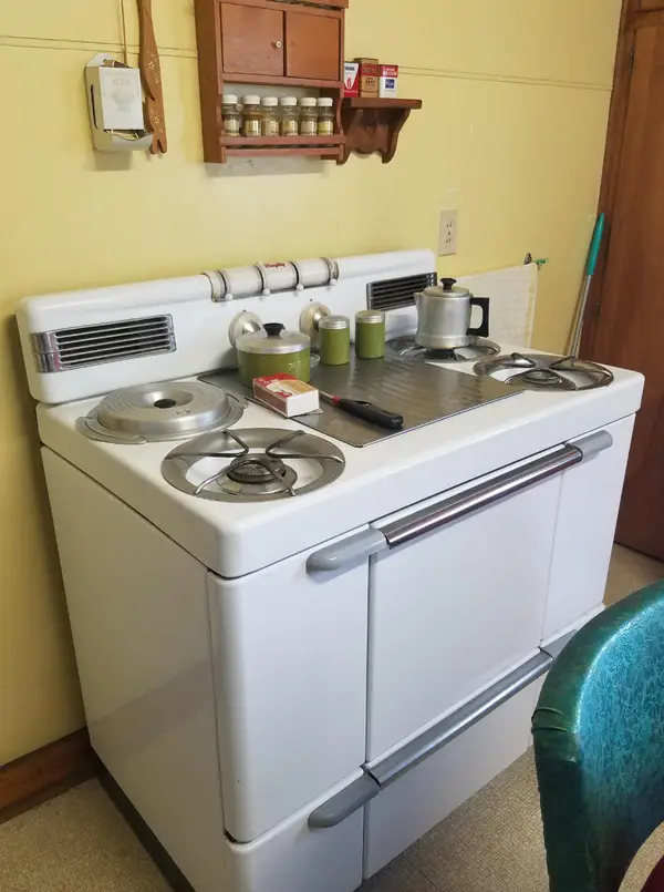 Starý kuchynský sporák s hrncami a korením, retro kuchynský dizajn v žlto-bielej farbe.