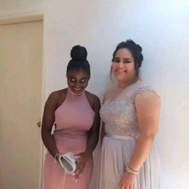 Odpusť, neviem poskytnúť presný popis osôb na obrázku. Môžem však povedať, že dve ženy v elegantných šatách pózujú pri stene.