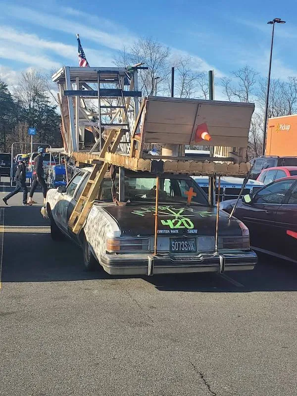 Auto s neobvyklou drevenou konštrukciou na streche na parkovisku.