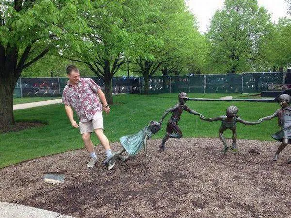 Muž sa priťahuje k bronzovej soche detí, ktoré sa držia za ruky v parku.