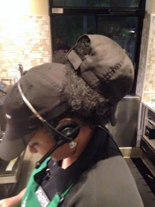 Pracovník v kaviarni s dvojakou čiapkou a headsetom pripravuje objednávku pri pultovom zariadení.