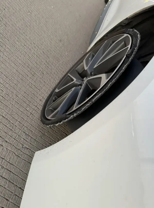 Pneumatika umiestnená na obrubníku, poškodený ráfik automobilu v tvare výrezu.