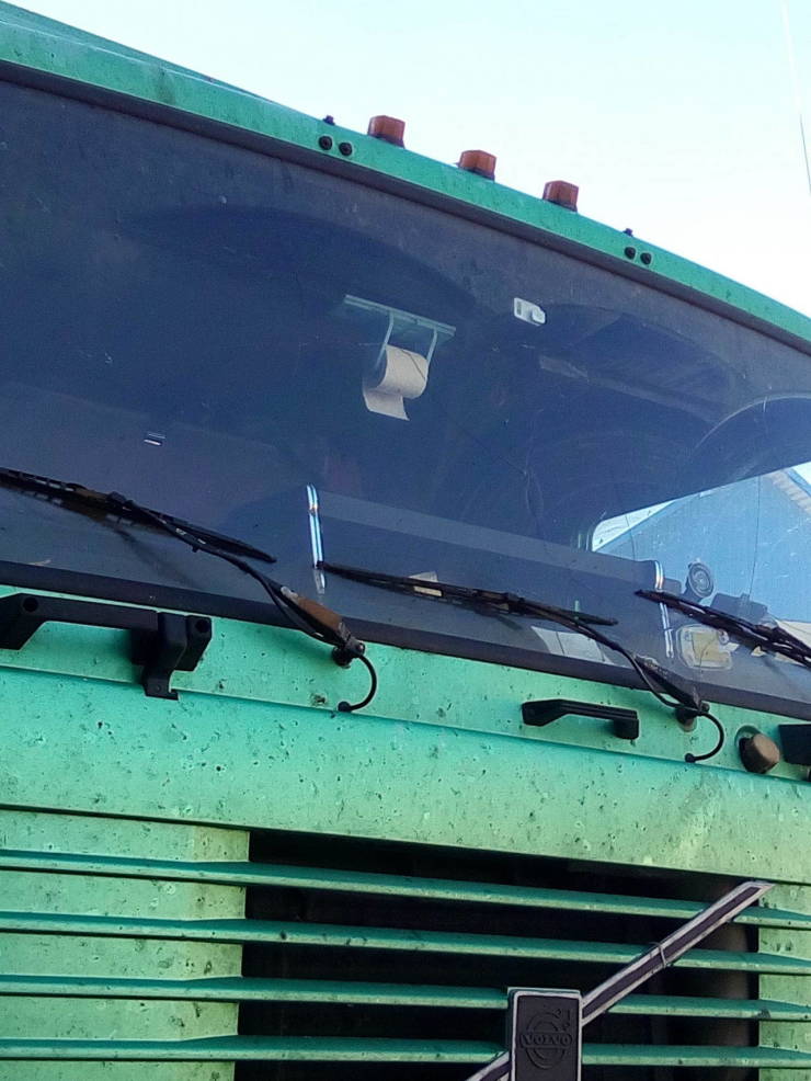 Zelený kamión s toaletným papierom na spätnom zrkadle v kabíne vodiča.