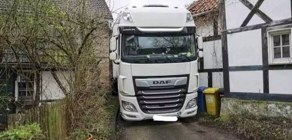 Kamión DAF zaparkovaný v úzkej uličke medzi dvoma domami.