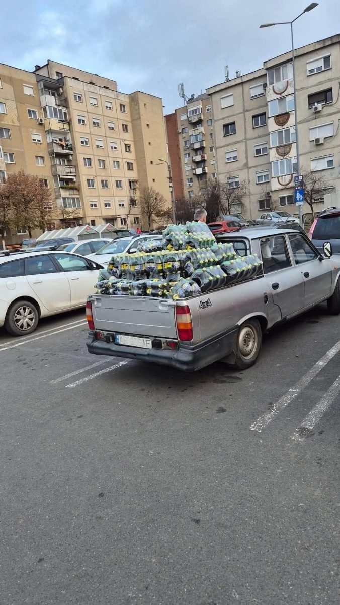 Auto na parkovisku preplnené fľašami s limonádou pred bytovým domom.