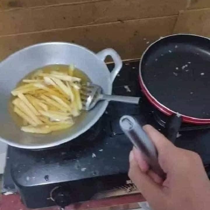 Smaženie hranoliek na panvici so striebornou rukoväťou na kuchynskom sporáku.