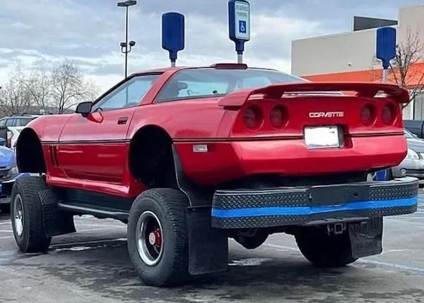 Červené športové auto na vysokých terénnych pneumatikách zaparkované na parkovisku.
