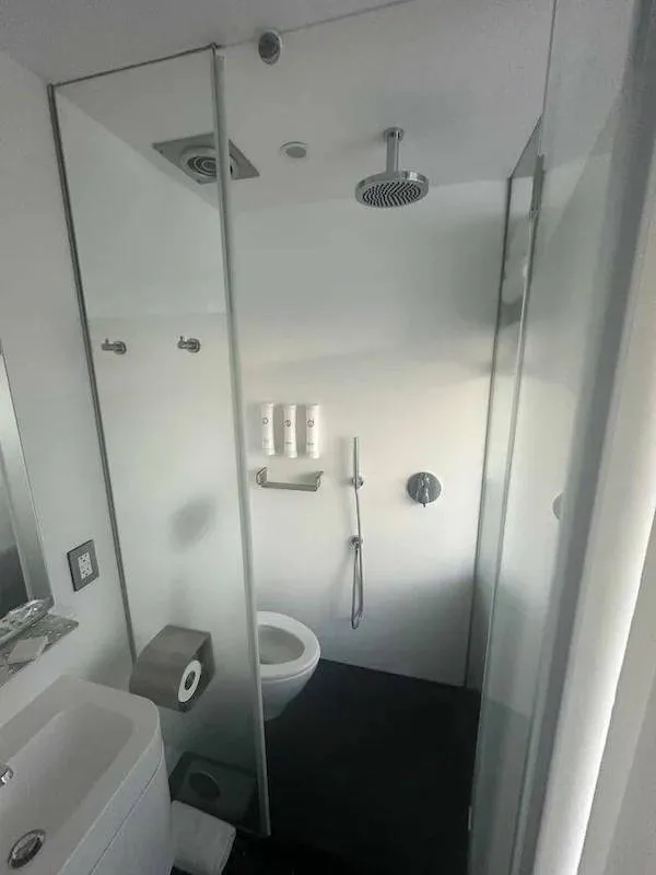 Moderná kúpelňa s toaletou, sprchovým kútom a bielymi stenami.