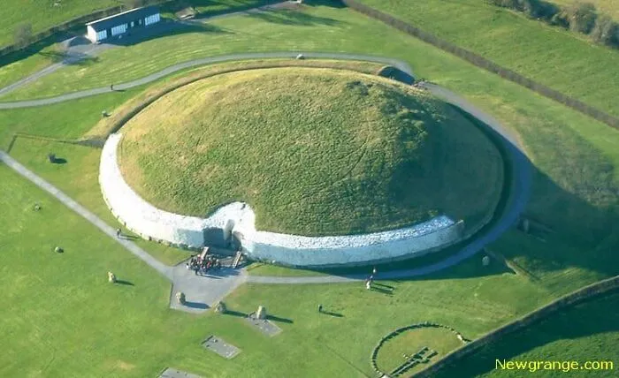 Veľkolepý pohľad na starodávnu hrobku Newgrange, obklopenú zelenou krajinou, z vtáčej perspektívy.