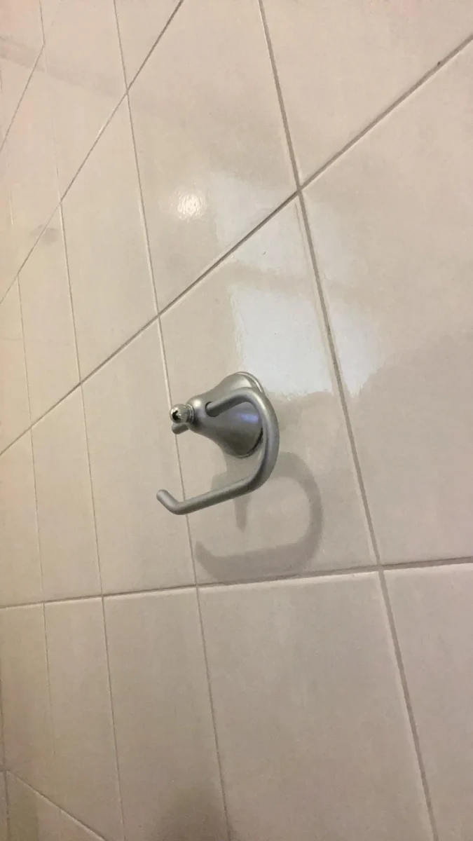 Držiak na uterák na bielej keramickej dlaždici v kúpeľni.