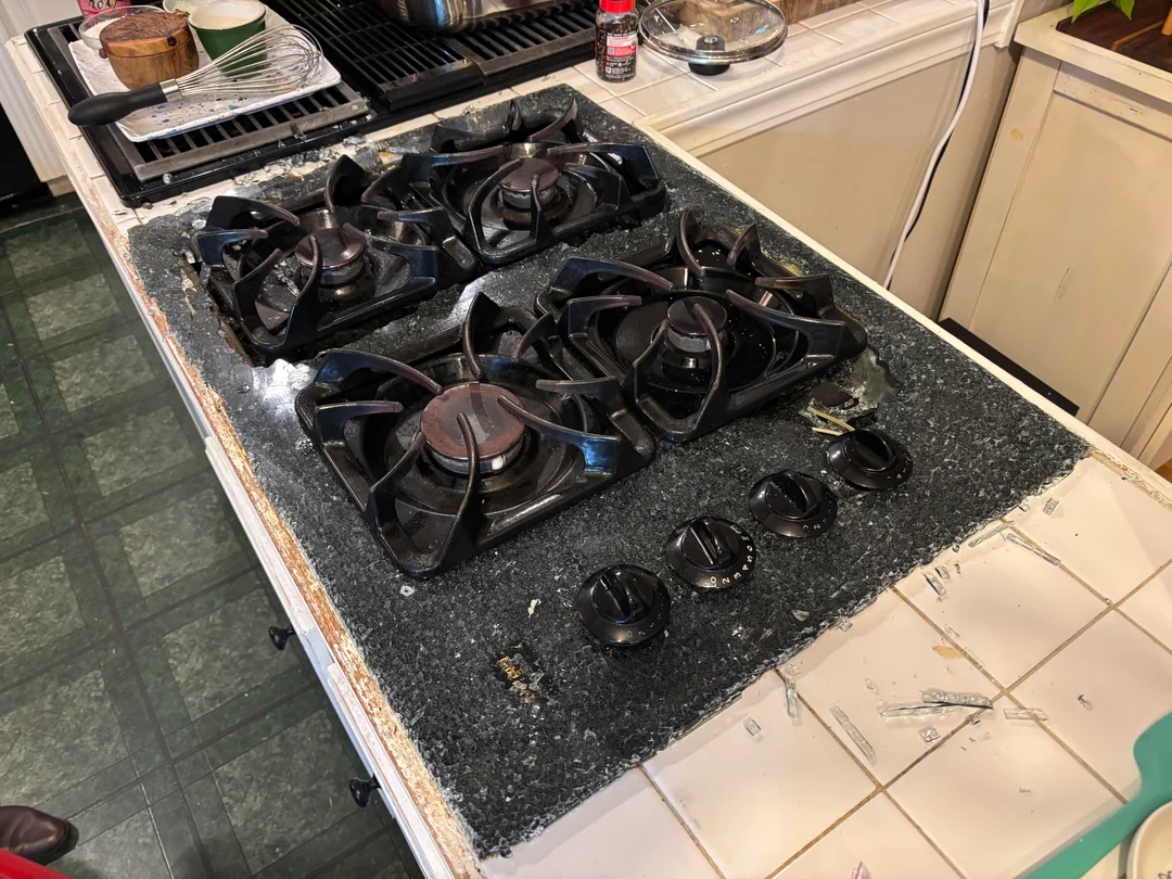 Rozbitá kuchynská sporáková doska s neporiadkom na blízkom stole.