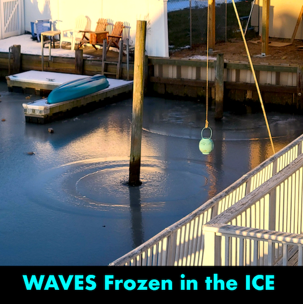 Zamrznuté vlny v prístave s člnom; chladné zimné ráno pri vode, zelená bója visí nad ľadom.