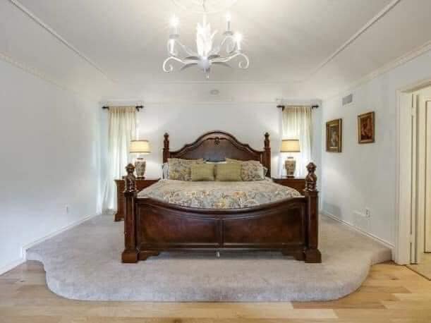 Luxusná spálňa so zaujímavým dreveným posteľným rámom a modernými doplnkami v bielom interiéri.