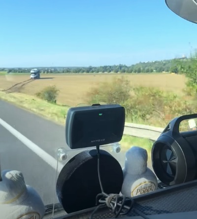 Pohľad z auta na cestu cez krajinu, GPS zariadenie na čelnom skle.