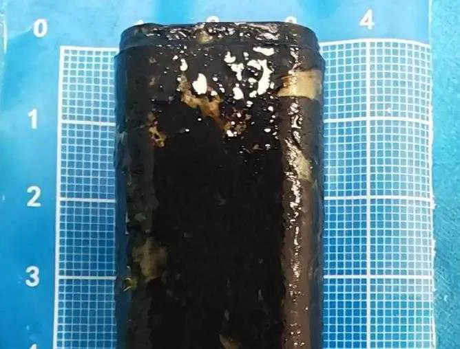 Čierny valcový objekt na modrej mriežkovej podložke s číslami.